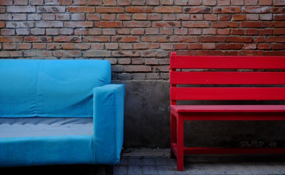 blue padded brown wooden chair beside brown brick wall