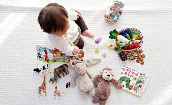 boy sitting on white cloth surrounded by toys